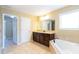 Luxurious bathroom with a large vanity with dark cabinets and a drop-in tub, all with natural light and tile floor at 335 Roberts Run Cv, Suwanee, GA 30024