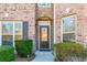 Inviting front entrance features a black front door with glass detailing and manicured shrubbery at 335 Roberts Run Cv, Suwanee, GA 30024