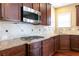 Kitchen featuring granite countertops, gas range, stainless microwave, dark wood cabinets, and tile backsplash at 335 Roberts Run Cv, Suwanee, GA 30024