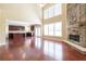 Open living space with tall windows, hardwood floors, and a stone fireplace as a focal point at 335 Roberts Run Cv, Suwanee, GA 30024
