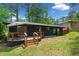Back of house features long deck, dark siding, and a grassy lawn that leads into the trees at 3964 Gretna Green Dr, Decatur, GA 30035