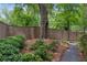 A tranquil backyard features a mature tree, lush greenery, and a gravel path alongside a wooden fence at 655 Mead Se St # 58, Atlanta, GA 30312