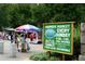 Outdoor farmers market with vendors, shoppers, and a sign promoting local and sustainable goods at 655 Mead Se St # 58, Atlanta, GA 30312