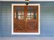 Close-up of the elegant wood double front doors with glass panels, framed by white trim and blue siding at 2142 Graystone Pkwy, Grayson, GA 30017