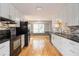 Well-lit kitchen with white cabinets, black countertops, stainless steel appliances, and hardwood floors at 2142 Graystone Pkwy, Grayson, GA 30017
