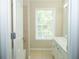 Bright bathroom featuring a window, neutral tile, and a combination shower and bathtub at 663 Prada Ct, Lawrenceville, GA 30043