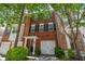 Charming brick townhome featuring black shutters, mature landscaping, and a convenient one-car garage at 2201 Landing Walk Dr, Duluth, GA 30097