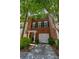 Charming brick townhome featuring black shutters, mature landscaping, and a convenient single-car garage at 2201 Landing Walk Dr, Duluth, GA 30097