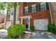 Charming brick townhome featuring a manicured shrub and a one-car garage providing practical storage and curb appeal at 2201 Landing Walk Dr, Duluth, GA 30097
