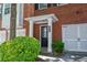 Inviting townhome front door next to garage entrance, complemented by lush shrubbery, enhancing curb appeal at 2201 Landing Walk Dr, Duluth, GA 30097