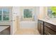 Bathroom featuring a soaking tub with tiled surround and a vanity with dark wood cabinets at 3231 Chutney Ct, Avondale Estates, GA 30002