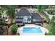 Aerial view shows the pool, deck with pergola, screened porch, and rear of the house at 4985 Miller Sw Rd, Lilburn, GA 30047