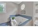 Relaxing bathroom featuring a soaking tub with blue tile, decor, and natural light at 4985 Miller Sw Rd, Lilburn, GA 30047