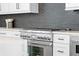 Kitchen with stainless steel oven and gas range, gray subway tile backsplash and white cabinetry at 88 Cleveland Unit B Se St, Atlanta, GA 30316