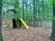 Playground fort featuring a slide and American flag in wooded backyard with trees and privacy fence at 1093 Spruce Creek Ln, Lawrenceville, GA 30045