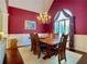 Elegant dining room with a chandelier, dark red walls, and large window at 1093 Spruce Creek Ln, Lawrenceville, GA 30045