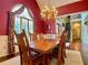 Elegant dining room with a chandelier, dark red walls, and large window at 1093 Spruce Creek Ln, Lawrenceville, GA 30045