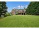 Spacious backyard featuring a lush lawn, mature trees, and a brick house with an inviting deck at 3689 Spring Hill Se Rd, Smyrna, GA 30080