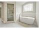 Bright bathroom features a glass shower and a modern soaking tub beneath an arched window at 3689 Spring Hill Se Rd, Smyrna, GA 30080