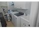 Well-lit laundry room equipped with modern washer, dryer, cabinets and utility sink at 6614 Covered Bridge Way, Braselton, GA 30548