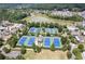 Aerial view of tennis courts surrounded by trees near a calm lake at 7275 Cordery Rd, Cumming, GA 30040