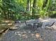 Backyard gravel seating area with outdoor dining table and chairs, nestled among trees at 204 Queensbury Ct, Acworth, GA 30102