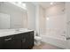Well-lit bathroom featuring a modern vanity with granite counters and bathtub with white tile surround at 2093 Callaway Nw Ct, Atlanta, GA 30318
