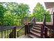 Inviting wooden deck featuring black metal railings and steps leading to a lush, wooded backyard at 219 Brick Mill Dr, Canton, GA 30115