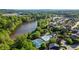 Aerial view of tennis courts, pool, lake, and homes in a community surrounded by lush greenery at 4830 Frontier Dr, Cumming, GA 30028