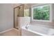 Bright bathroom with a soaking tub, glass-enclosed shower, and a large window at 4830 Frontier Dr, Cumming, GA 30028
