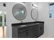 Modern bathroom featuring a double vanity, granite countertop, round mirrors, and contemporary lighting fixtures at 90 Cleveland Unit A Se St, Atlanta, GA 30316