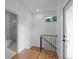 Bright hallway with wood floors, modern railing, and an adjacent bathroom featuring a tiled shower at 90 Cleveland Unit A Se St, Atlanta, GA 30316