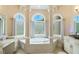 Relaxing bathroom with a sunken tub and arched windows offering lots of natural light at 2425 Wild Oak Ct, Stockbridge, GA 30281