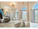 Bathroom with and sinks, framed mirrors, and a separate tub beneath arched windows at 2425 Wild Oak Ct, Stockbridge, GA 30281