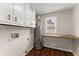 Bright laundry room with white cabinets, wooden countertop, dark hardware, and modern fixtures at 2979 Overwood Sw Ln, Snellville, GA 30078