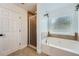 Bright bathroom with white door, walk-in shower, and soaking tub under a large window at 632 Warren Ave, Scottdale, GA 30079