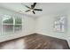 Bedroom with dark wood floors, two bright windows, ceiling fan and white trim at 632 Warren Ave, Scottdale, GA 30079