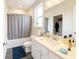 Well-lit bathroom features a bathtub with shower, a large mirror, and plenty of counter space, showcasing practicality at 125 Leveret Rd, Locust Grove, GA 30248