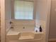Modern soaking tub featuring white tile surround and a window for natural light at 2257 Rocksram Ct, Buford, GA 30519