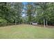 Large, grassy backyard surrounded by mature trees and a wooden fence, with a shed at 4326 Megan Manor Sw Dr, Powder Springs, GA 30127
