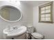 Half bathroom with white wainscoting, an oval mirror, and a window at 5152 Clearwater Dr, Stone Mountain, GA 30087