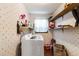 Laundry room with floral wallpaper, overhead shelves, and a front load washing machine at 5152 Clearwater Dr, Stone Mountain, GA 30087