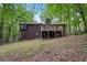 Back exterior featuring a wooden deck on a lush lot surrounded by mature trees at 3679 Regent Nw Dr, Kennesaw, GA 30144