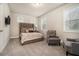 Bedroom with neutral walls and carpet, large window, bed with tufted headboard, and occasional chairs at 704 Fairlane Dr, Marietta, GA 30064