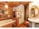 Log-style bathroom with wood paneling, a built-in tub, and a charming pedestal sink at 20 Mahan Ne Ln, Rydal, GA 30171