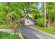 View of the driveway leading to a carport, surrounded by mature trees and lush landscaping at 3109 Country Lake Dr, Powder Springs, GA 30127