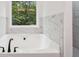 Bright bathroom featuring a soaking tub with matte black fixtures and a view of the surrounding trees at 2279 Lakeview Pkwy, Villa Rica, GA 30180