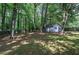 Expansive backyard with mature trees, a charming detached two-car garage, and privacy fence at 3710 Lavilla Dr, Powder Springs, GA 30127