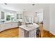 Open kitchen featuring white cabinets, an island with seating, and stainless steel appliances and hardwood floors at 4585 Lakefield Bnd, Berkeley Lake, GA 30096