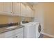 Bright laundry room with granite countertops, tile floor, upper storage, and modern washer and dryer at 2853 N Thompson Ne Rd, Brookhaven, GA 30319